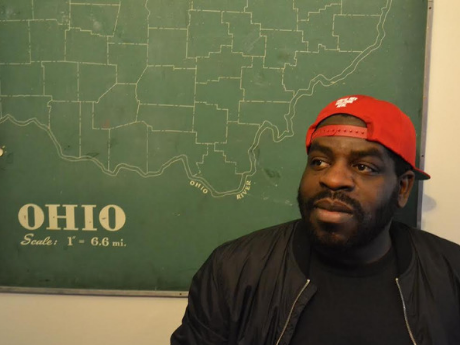 Hanif Abdurraqib sitting in front of a map of Ohio