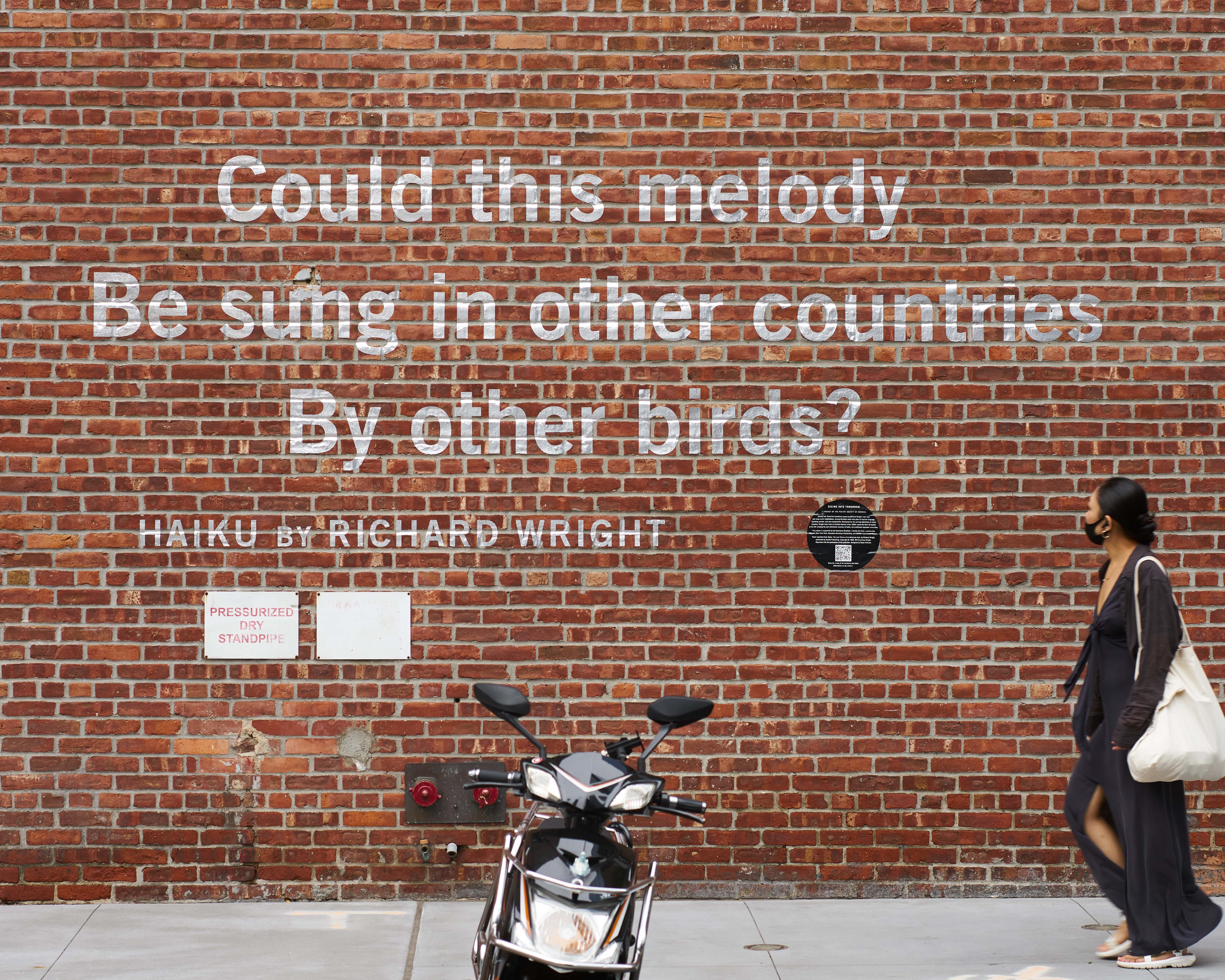 A haiku painted on a brick wall. The text reads: Could this melody Be sung in other countries By other birds? Hiaku by Richard Wright