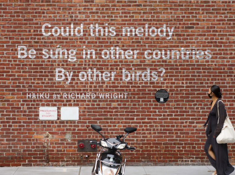 A haiku painted on a brick wall. The text reads: Could this melody Be sung in other countries By other birds? Hiaku by Richard Wright